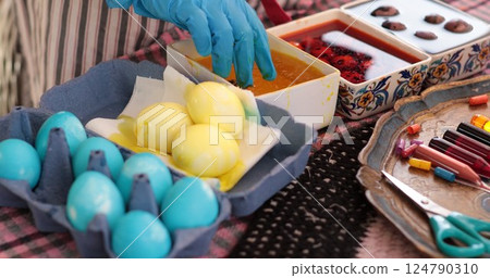 Creating beautiful Easter eggs with yellow and blue colors, a fun activity of colouring eggs that showcases traditional Ukrainian pysanky techniques 124790310
