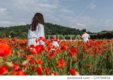 rear view of group of three girls walking in a poppy field 124790658