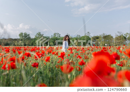 one HAPPY girl walking in a big poppy field 124790660