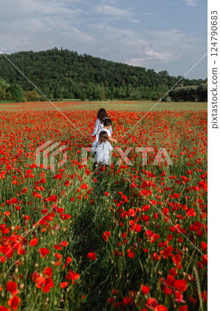 rear view of three children walking in a poppy field 124790683