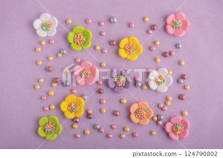 Easter decor for cake: colorful sugar sparkles and flowers on pastel puple background. Top view 124790802