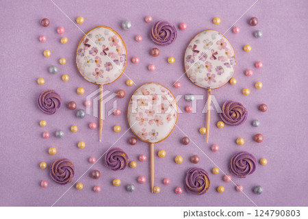 Easter decor for cake: easter eggs, colorful sugar sparkles and flowers on pastel puple background. Top view 124790803