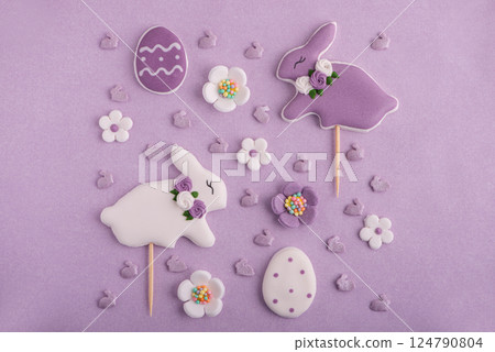 Easter decor for cake: funny easter bunnies, easter eggs, colorful sugar sparkles on pastel puple background. Top view 124790804