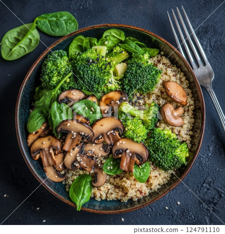 Quinoa salad with broccoli and mushrooms in a dark bowl on a rustic surface 124791110