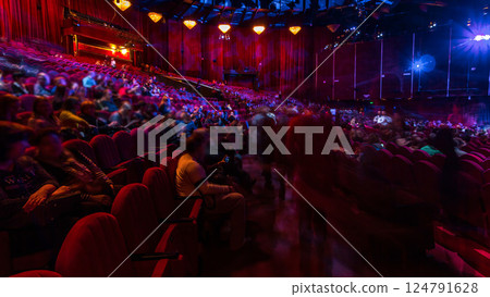 Spectators gather in the auditorium and watch the show in theatre timelapse. Large hall with red armchairs seats 124791628