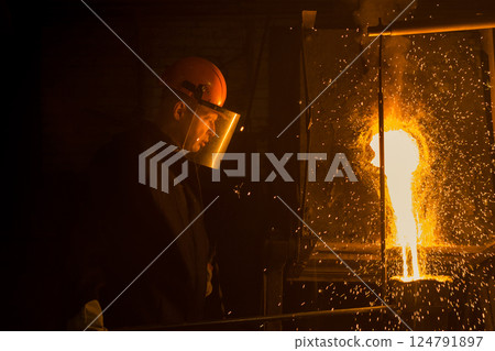 smelter worker pours liquid metal into a casting mold smelter worker pours liquid metal into a casting mold 124791897