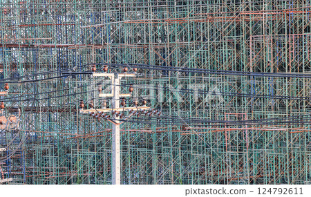 High voltage post, High voltage tower in front of a large number of scaffoldings are used in large construction projects.  124792611