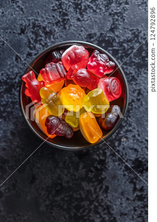The colorful jelly candies in bowl on black table. Top view. The colorful jelly candies in bowl on black table. Top view. 124792896