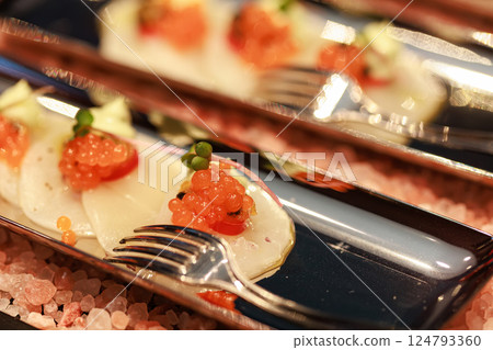 Elegant seafood appetizer featuring thinly sliced scallops, garnished with vibrant salmon roe 124793360