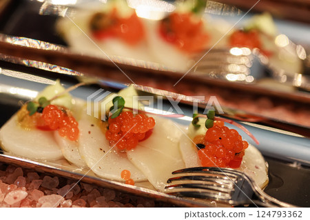Elegant seafood appetizer featuring thinly sliced scallops, garnished with vibrant salmon roe Elegant seafood appetizer featuring thinly sliced scallops, garnished with vibrant salmon roe 124793362