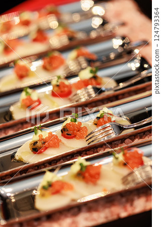 Elegant seafood appetizer featuring thinly sliced scallops, garnished with vibrant salmon roe 124793364