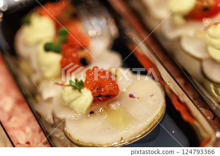 Elegant seafood appetizer featuring thinly sliced scallops, garnished with vibrant salmon roe 124793366