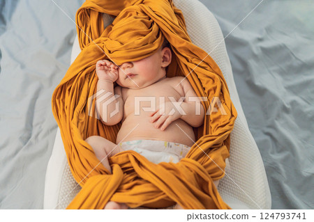 Newborn baby comfortably resting in a cozy baby nest. Safe and peaceful sleep concept for infants 124793741