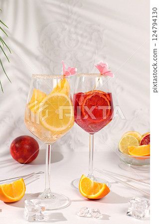 Aperol Spritz cocktails with lemon and orange, ice cubes, rum and tequila. Summer party and holiday concept. Banner with alcoholic drinks and tropical fruits. Menu for a bar or cafe. Aperol Spritz cocktails with lemon and orange, ice cubes, rum and tequila. Summer party and holiday concept. Banner with alcoholic drinks and tropical fruits. Menu for a bar or cafe. 124794130