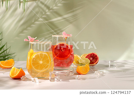 Royal cocktail of blood orange, lemon and lime, ice cubes, rum and tequila. Flyer with a glass of alcoholic drink and tropical fruits. Summer party concept. Menu for a bar or cafe. Royal cocktail of blood orange, lemon and lime, ice cubes, rum and tequila. Flyer with a glass of alcoholic drink and tropical fruits. Summer party concept. Menu for a bar or cafe. 124794137