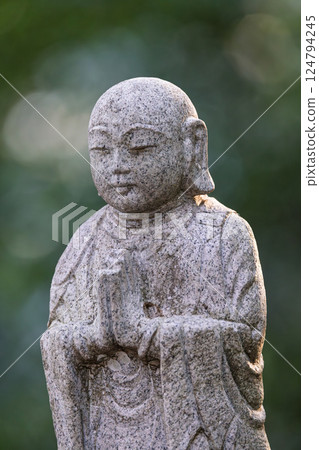A stone statue of Buddha smiling and putting his hands together 124794245