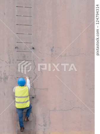Engineer, building and man climbing ladder to get to roof or construction site. Engineering, safety and male maintenance, repair or installation contractor or worker going up steps on wall mock up. Engineer, building and man climbing ladder to get to roof or construction site. Engineering, safety and male maintenance, repair or installation contractor or worker going up steps on wall mock up. 124794314