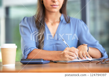 Business woman, accountant and notebook while writing notes and using calculation for budget, profit and bookkeeping while sitting at a desk. Hands of entrepreneur with planner for financial report 124794397