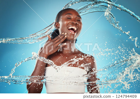 Water, splash and woman washing for hygiene and grooming on a blue studio background. Young black woman wash, cleanse and cleansing body and skin for bodycare, skincare and health or wellness 124794409
