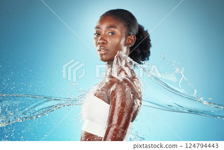 Black woman, water and cleaning body for health, skincare and beauty against blue mockup studio background. Splash, cosmetics and model with water splash for washing skin and wellness with mock up 124794443
