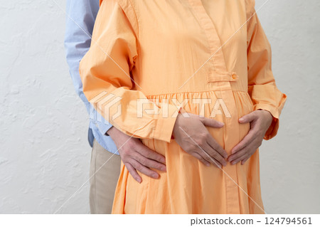 A husband holds his pregnant wife close to his stomach A husband holds his pregnant wife close to his stomach 124794561