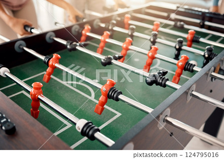 Foosball, game and fun with people playing a game inside of a clubhouse or at a party together. Soccer, table and competition with friends bonding over a match of football together for recreation Foosball, game and fun with people playing a game inside of a clubhouse or at a party together. Soccer, table and competition with friends bonding over a match of football together for recreation 124795016