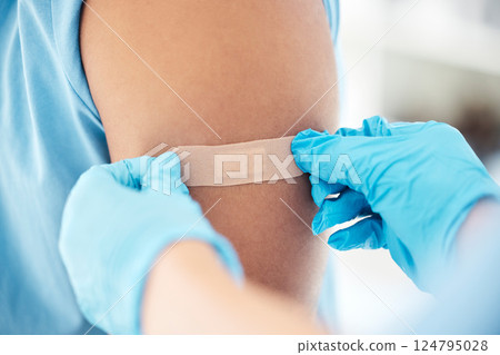 Bandaid, vaccine and arm of patient at the doctor for healthcare, medical attention and consultation with covid. Hands of a hospital nurse with a plaster for an injury, virus or safety while sick 124795028
