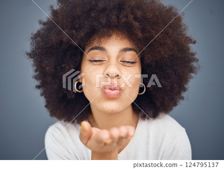 Kissing, love and romance with a black woman blowing a kiss in studio on a gray background for romantic affection. Beauty, lips and flirt with an attractive young female making a mouth gesture 124795137