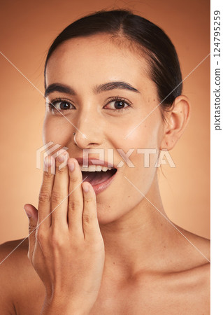 Wow, gossip, and woman with hand for beauty, makeup and cosmetics against a brown studio background. Skincare, happy and young model with surprise from cosmetic care, cosmetology and dermatology 124795259