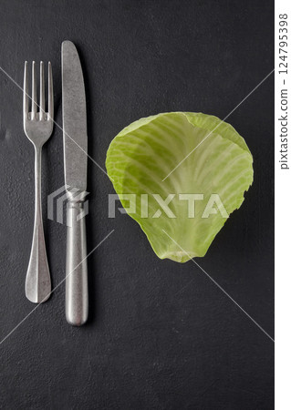 cabbage leaf and cutlery fork with knife on black table. weight loss diet concept cabbage leaf and cutlery fork with knife on black table. weight loss diet concept 124795398