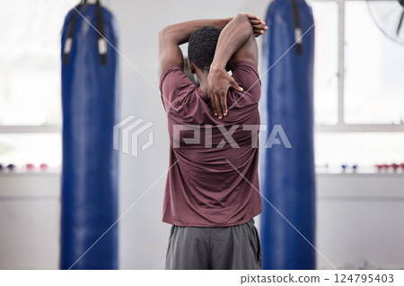 Boxer stretch, black man and athlete at a gym stretching arms before training and sports. Fitness, exercise and boxing health of a male fighter doing a back muscle workout for martial arts in a dojo Boxer stretch, black man and athlete at a gym stretching arms before training and sports. Fitness, exercise and boxing health of a male fighter doing a back muscle workout for martial arts in a dojo 124795403