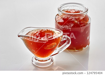 Fruit apple jam in glass jar and sauce boat on white table Fruit apple jam in glass jar and sauce boat on white table 124795404