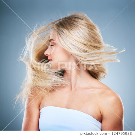 Woman, hair and blonde with wind in studio for hair care, cosmetics and beauty against blue background. Model, girl and healthy hair from side by blue backdrop with shake, turn and cosmetic fashion Woman, hair and blonde with wind in studio for hair care, cosmetics and beauty against blue background. Model, girl and healthy hair from side by blue backdrop with shake, turn and cosmetic fashion 124795988