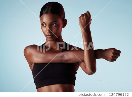 Fitness, studio and woman stretching shoulder and arms in a warm up to start training, workout and cardio exercise. Focus, wellness and healthy young sports girl relaxing her strong body muscles 124796132