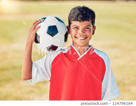 Boy portrait, field and soccer ball with smile for sport, fitness or training at soccer game, contest or competition. Athlete kid, football and happy with ball on shoulder for sports outdoor on grass 124796164