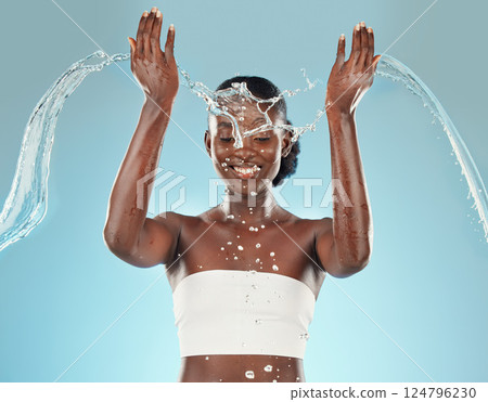 Water, splash and black woman washing on a blue studio background for hygiene and grooming. Clean, cleansing and bodycare or skincare for african american female showering for beauty and wellness Water, splash and black woman washing on a blue studio background for hygiene and grooming. Clean, cleansing and bodycare or skincare for african american female showering for beauty and wellness 124796230