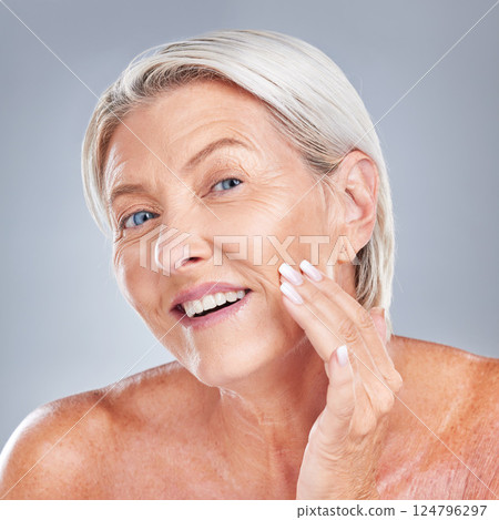 Skincare, wellness and senior woman with face for inspection, health and beauty against a grey studio background. Happy, smile and portrait of an elderly person with facial care during retirement 124796297