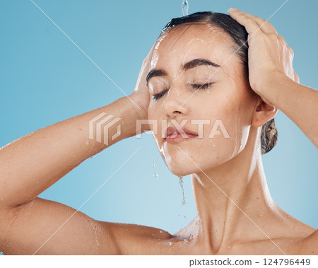 Shower, water and woman cleaning her body on a blue studio background. Bodycare, haircare and health or wellness with a young female cleansing her face, getting wet for fresh and cosmetic skin 124796449