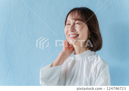 中年婦女撫摸她的頭髮（藍色背景） 124796723