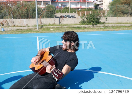 Long Hair Man Plays Classical Guitar Unleashed Outside In Blue Field Long Hair Man Plays Classical Guitar Unleashed Outside In Blue Field 124796789