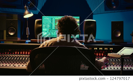 Audio technician working in control room to edit and process tracks, using audio software on pc for music industry post production. Skilled producer creating tunes with mixing console. Camera B. Audio technician working in control room to edit and process tracks, using audio software on pc for music industry post production. Skilled producer creating tunes with mixing console. Camera B. 124797017