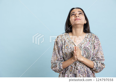 Wishful calm woman praying to jesus christ with folded hands in studio, looking up and talking to god. Young faithful religious girl showing her spiritual belief, devotion and respect. Wishful calm woman praying to jesus christ with folded hands in studio, looking up and talking to god. Young faithful religious girl showing her spiritual belief, devotion and respect. 124797038