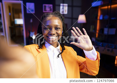 Portrait of ecstatic teenager filming content for online streaming channel in apartment studio, entertaining fans. Gen z influencer at home interacting with subscribers, doing greeting hand gesture Portrait of ecstatic teenager filming content for online streaming channel in apartment studio, entertaining fans. Gen z influencer at home interacting with subscribers, doing greeting hand gesture 124797066