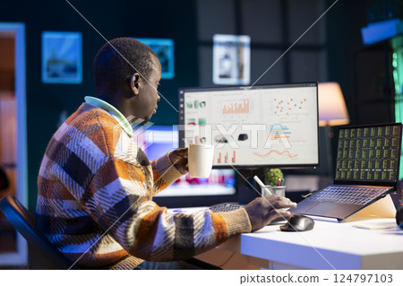 Research specialist reviewing financial elements and expenses to create strategic report for revenue growth. African american financier examines capital funds balance, remote work. 124797103