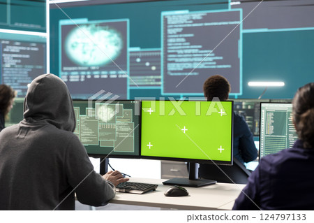Team of governmental hackers look at green screen in high tech agency office, working together on hacking database systems for cyberwarfare activity. Experts conducting illegal scams. Team of governmental hackers look at green screen in high tech agency office, working together on hacking database systems for cyberwarfare activity. Experts conducting illegal scams. 124797133