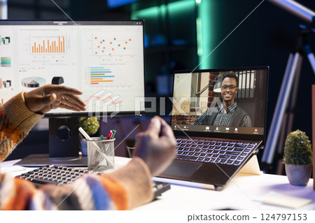 Young adult employee attends a meeting on video conference, presenting the current economic situation within the enterprise. African american guy having virtual communication with coworkers. 124797153