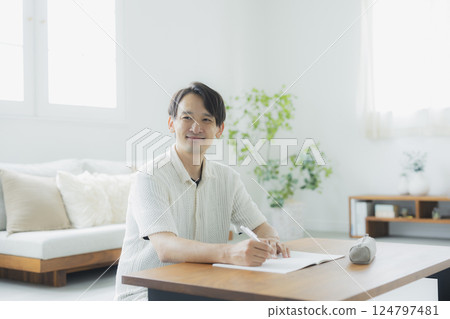 A man in his 30s studying in the living room A man in his 30s studying in the living room 124797481