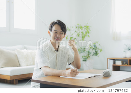 A man in his 30s studying in the living room A man in his 30s studying in the living room 124797482
