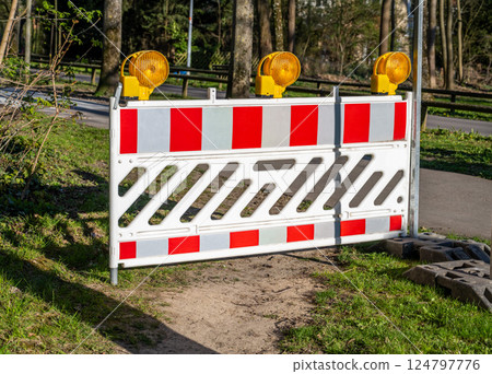 protective fencing with reflective strips and signal lights installed on the road 124797776