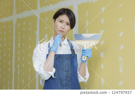 一名婦女正在為石膏板塗膩子 124797937